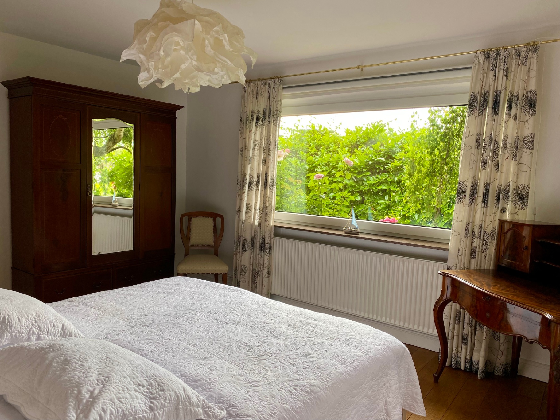Schlafzimmer mit antikem Kleiderschrank und weißem Bett im Ferienhaus
